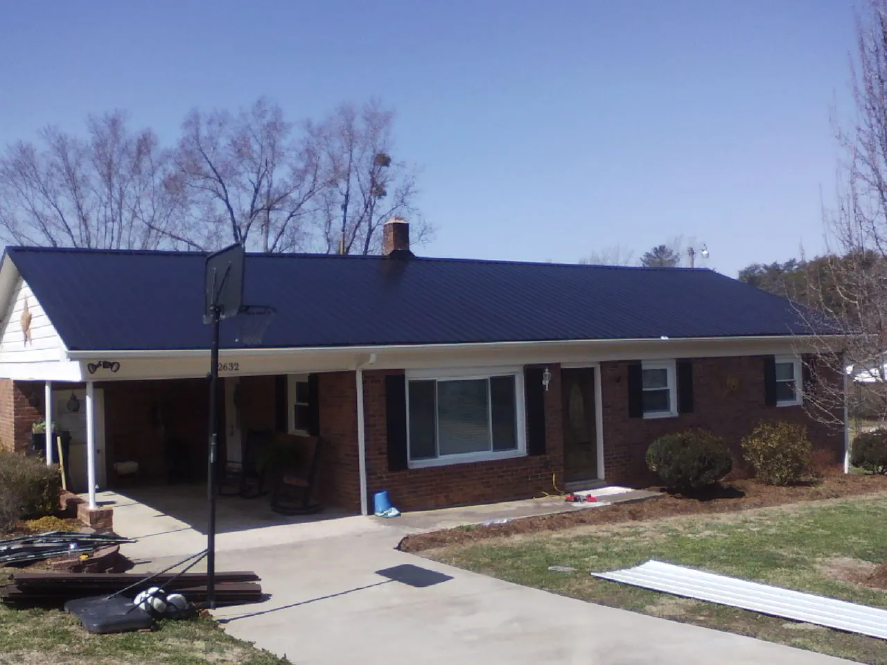 Finished dark blue metal roof on a brick ranch with a carport in North Liberty