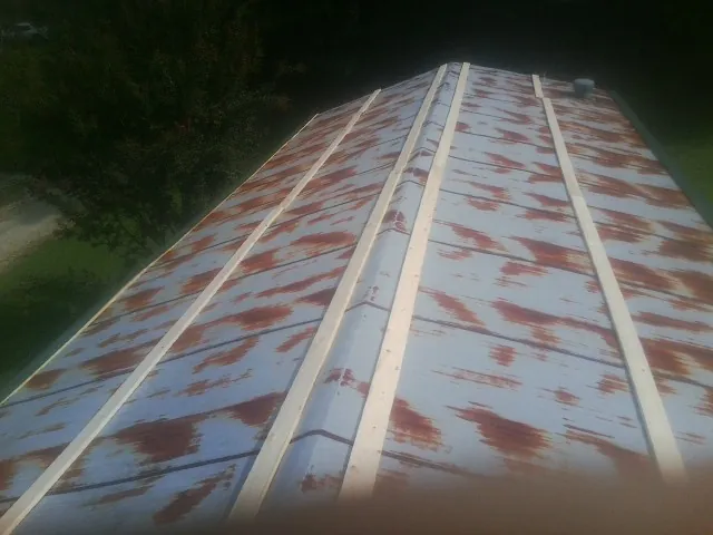 Rusted metal roof panels with new wood purlins before replacement — Storm Damage Roof Repair in North Liberty by Roofing Brothers