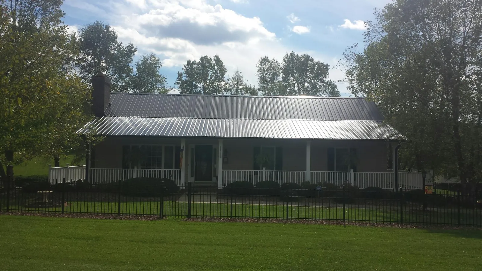 Gray metal roof on a brick ranch with a full width front porch — Gutter Guard Installation work by our crew in North Liberty